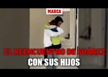 Reencuentro emotivo de un padre abrazando a su hijo en la entrada de una casa