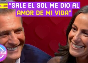 Pareja sonriente en una entrevista televisiva con el logo de Sale el Sol y un fondo rojo con corazones
