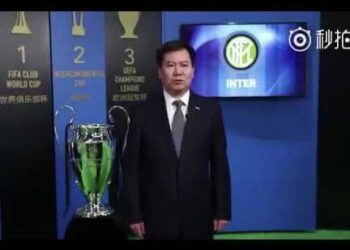 Patrimonio del magnate detrás del Inter de Milán: hombre de negocios en traje junto a un trofeo y el escudo del club.